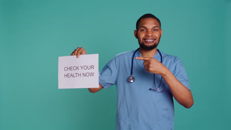 Portrait-of-male-nurse-holding-sign-urging-people-to-do-medical-appointments