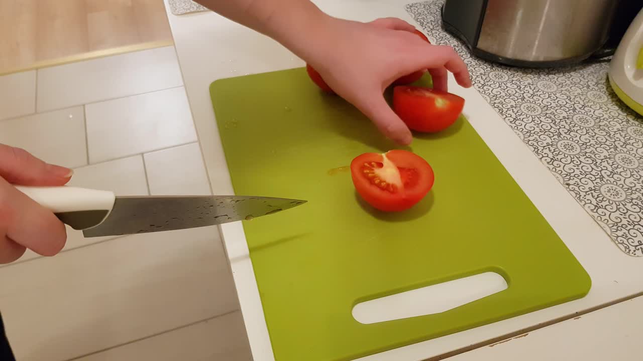 mujer caucásica cocinando y cortando tomates