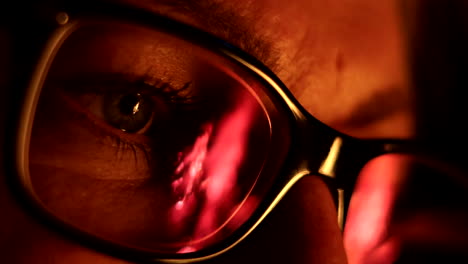 close-up of a woman glasses, reflecting fire flames at night, her blue eyes creating a relaxed ambiance