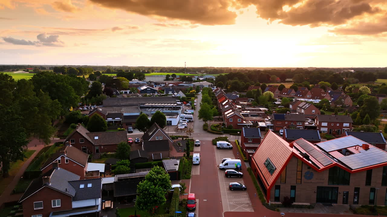 Dramatic clouds colored in orange in the sky over the town. Footage over the street in the countryside of the Netherlands at sunset