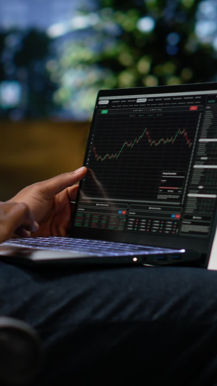 Vertical Video Black man navigating stock trading indicators online on laptop