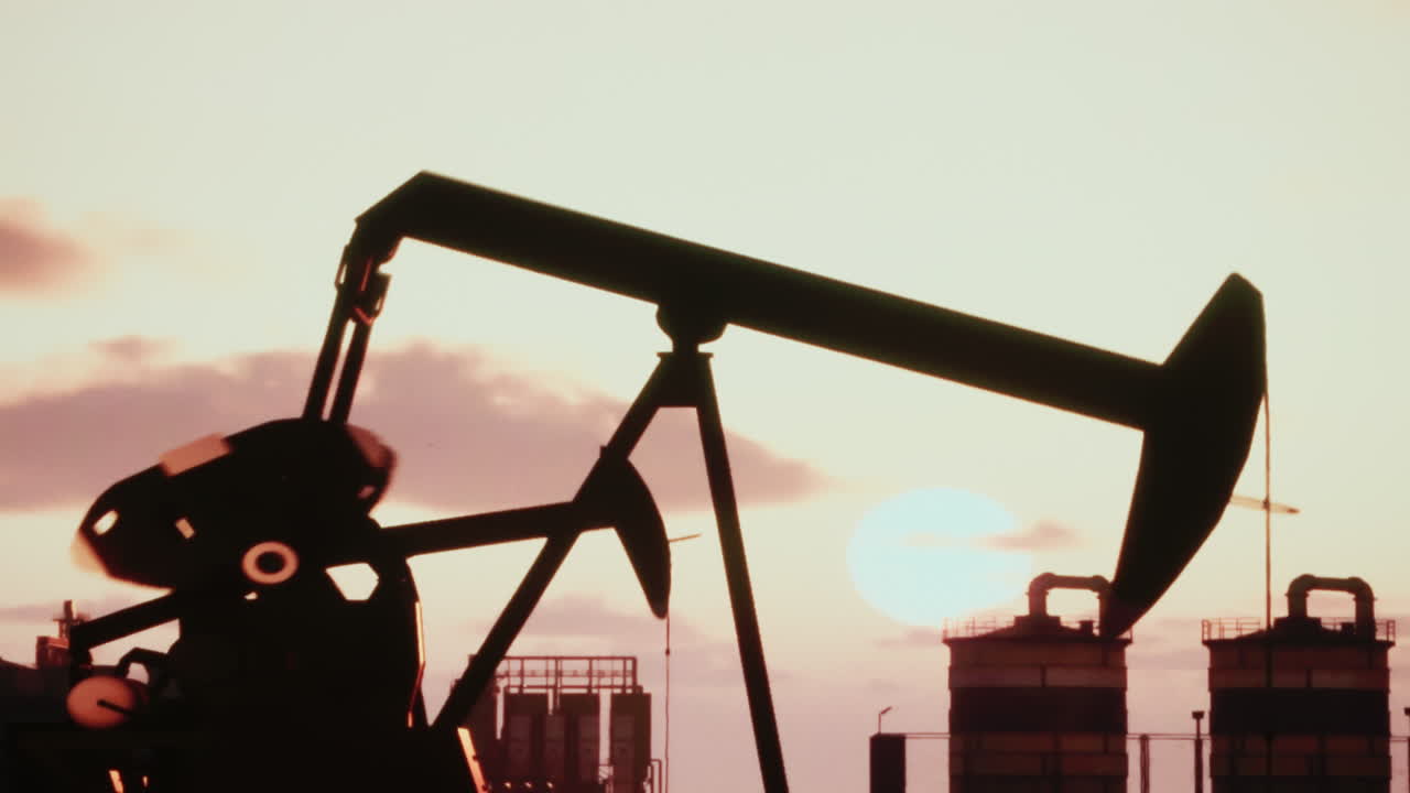 Oil Pumpjack Silhouette Against Sunset Sky