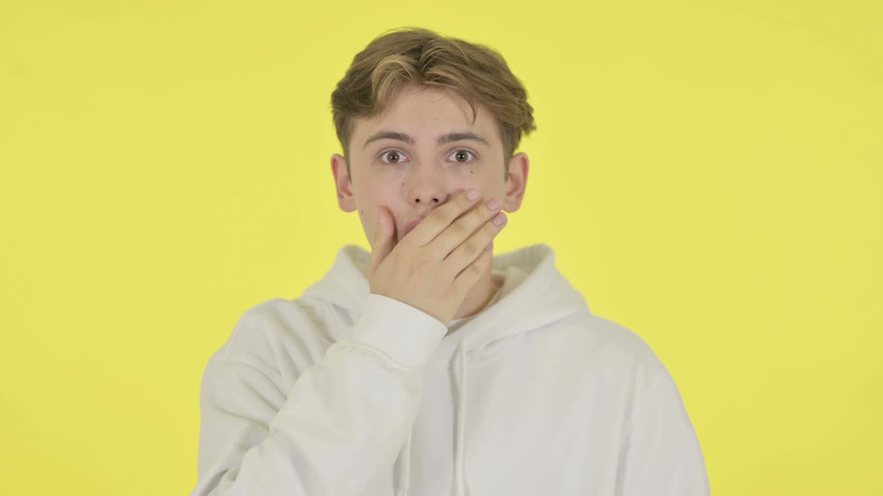 노란색 배경에 충격을 받은 젊은이