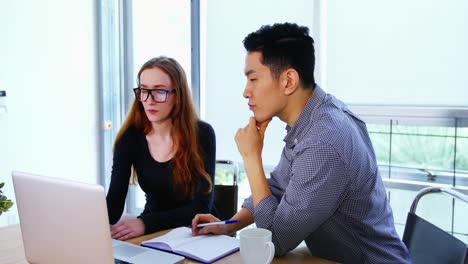 Business-executives-discussing-over-laptop