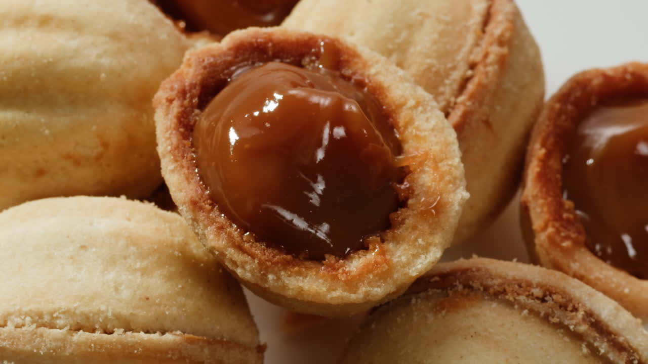 집에서 만든 견과류 모양의 쿠키와 여진 응축 우유가 회색 테이블에 평평하게 놓여 있습니다. 고품질의 4k 영상