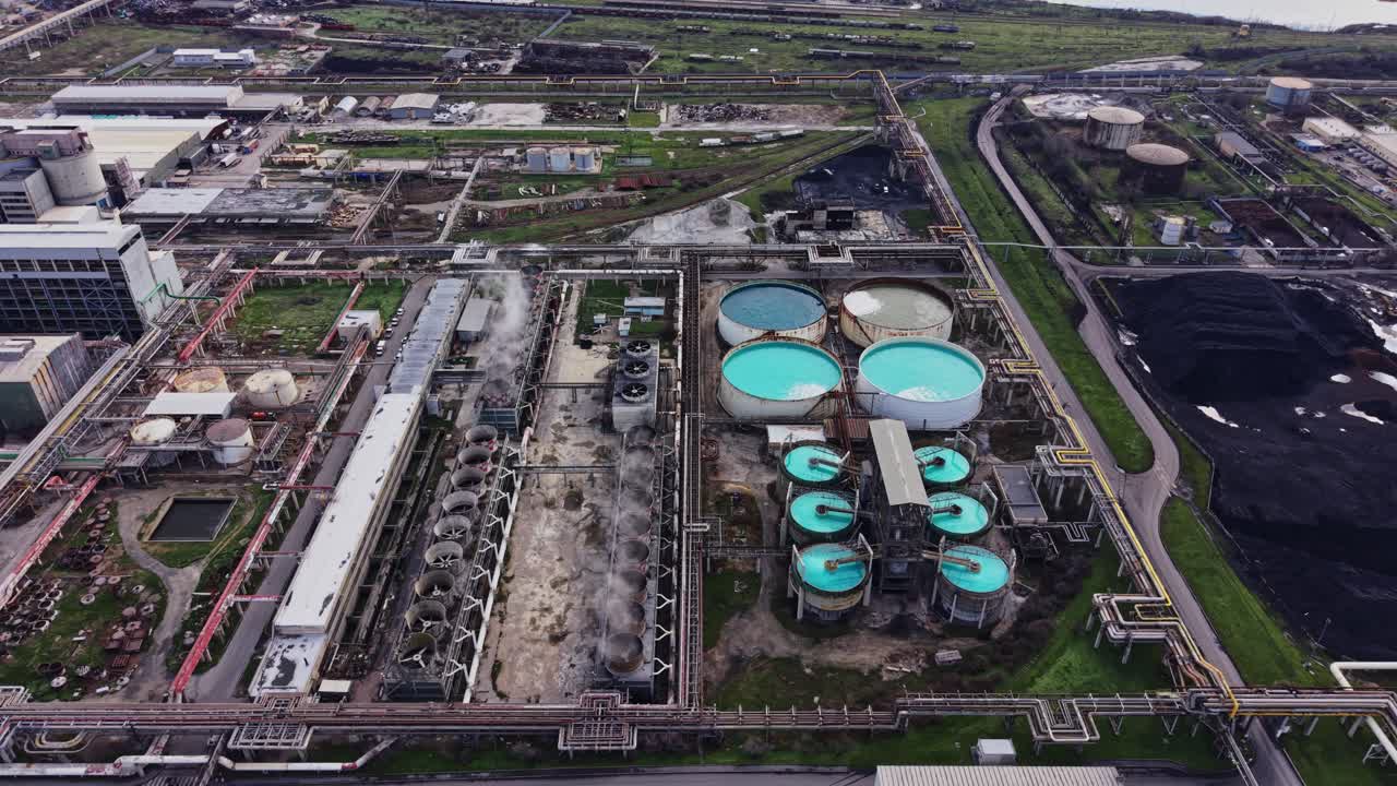 Industrial site with tanks and pipes near coastal area in broad daylight