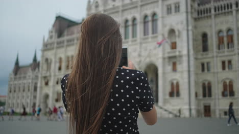 woman taking photo of the hungarian parliament building