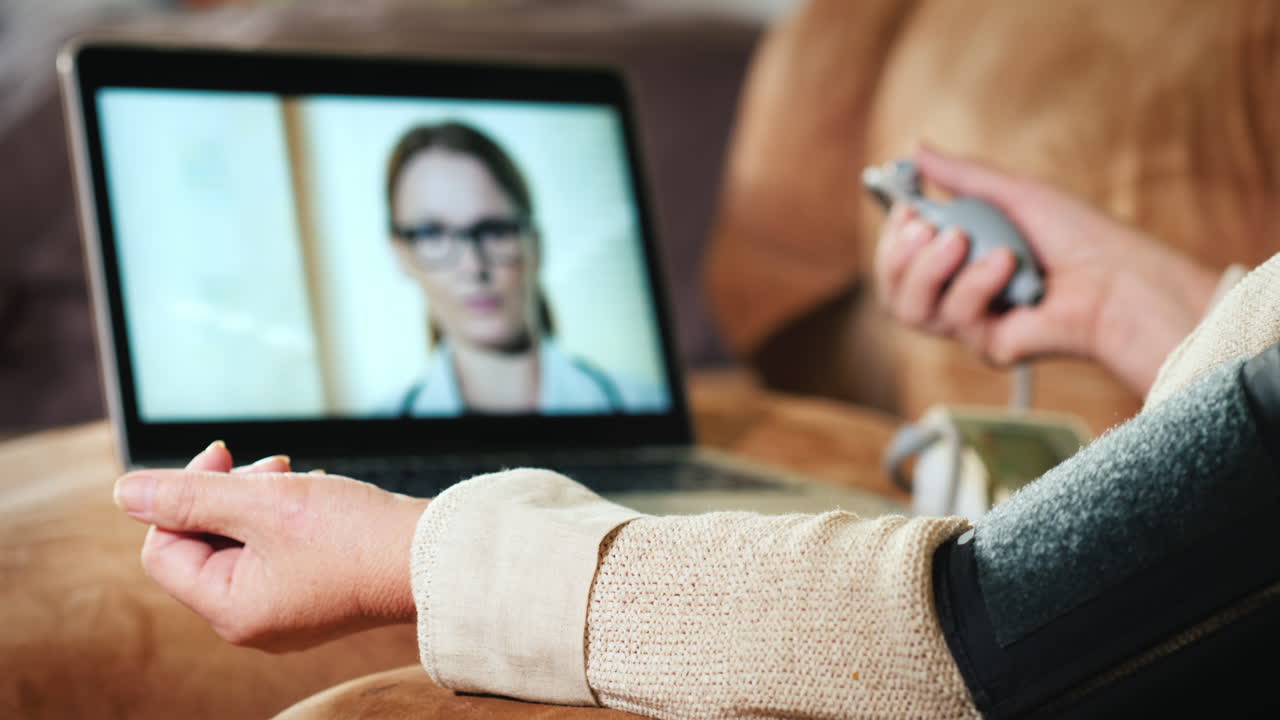Ältere Frau konsultiert Arzt per Webcam und misst Blutdruck