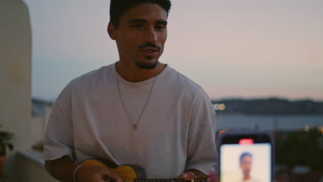 las manos de la chica grabando el hombre tocando la guitarra video terraza del atardecer. el chico cantando una canción