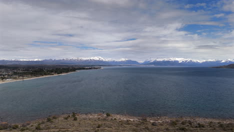 a tranquil view of nahuel huapi lake with snowy mountains and a vast blue sky