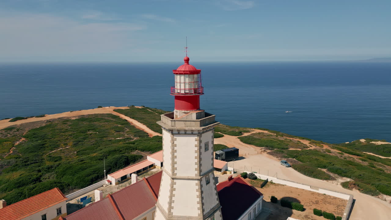 Ocean lighthouse standing sunny coast over endless marine horizon aerial view.