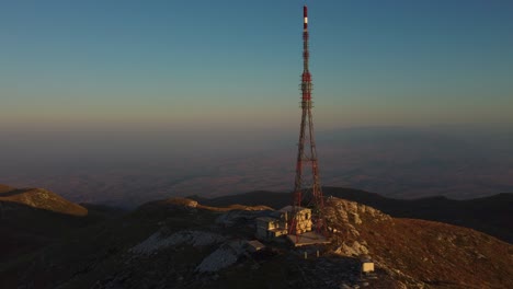 Antena-Acercándose-A-Una-Gran-Torre-De-Telecomunicaciones-En-La-Cima-De-Una-Montaña-Al-Amanecer