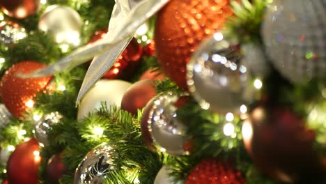 closeup of festively decorated outdoor christmas tree with bright red balls on blurred sparkling fairy background. defocused garland lights, bokeh effect. merry christmas and happy holidays concept.