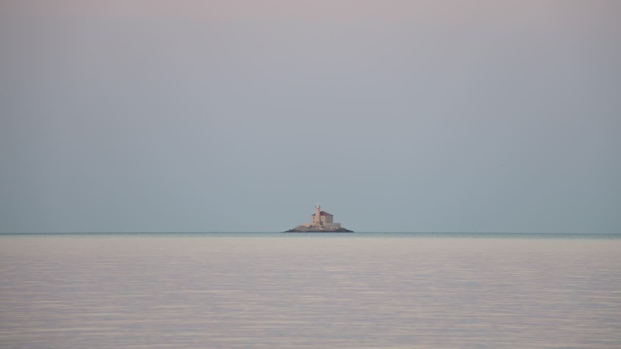 Stone lighthouse Mulo far on the horizon in front of small tourist town of Rogoznica, Croatia