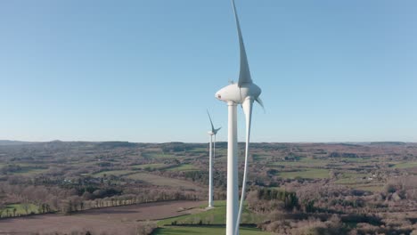 two large electricity generating windmills turning in the clear blue sky