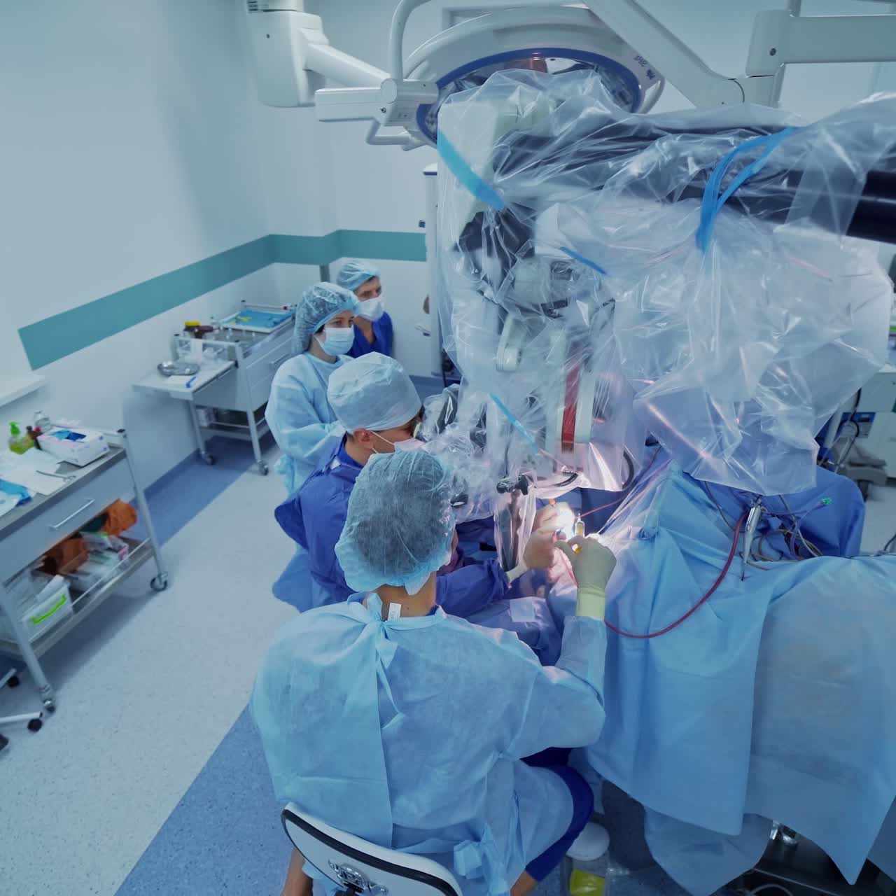 Medical specialists during neurosurgery. Doctors perform an operation looking into the microscope in modern hospital surgical room. Top view.