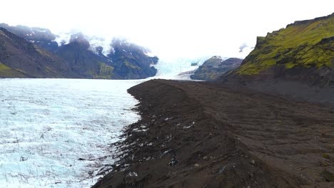 Aerial-view-of-melting-glacier-in-the-icelandic-mountains,-in-a-rocky-valley