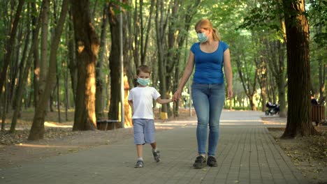 mother and son in medical masks walk in the park 01