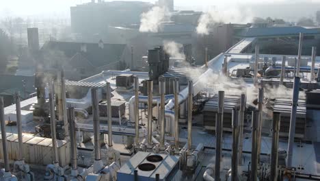 Industriedach-Mit-Abluftrohren-Und-Lüftungsschächten,-Klimaanlage,-Luftverschmutzungskonzept,-Dampf-Und-Rauch-Entweichen-In-Die-Luft