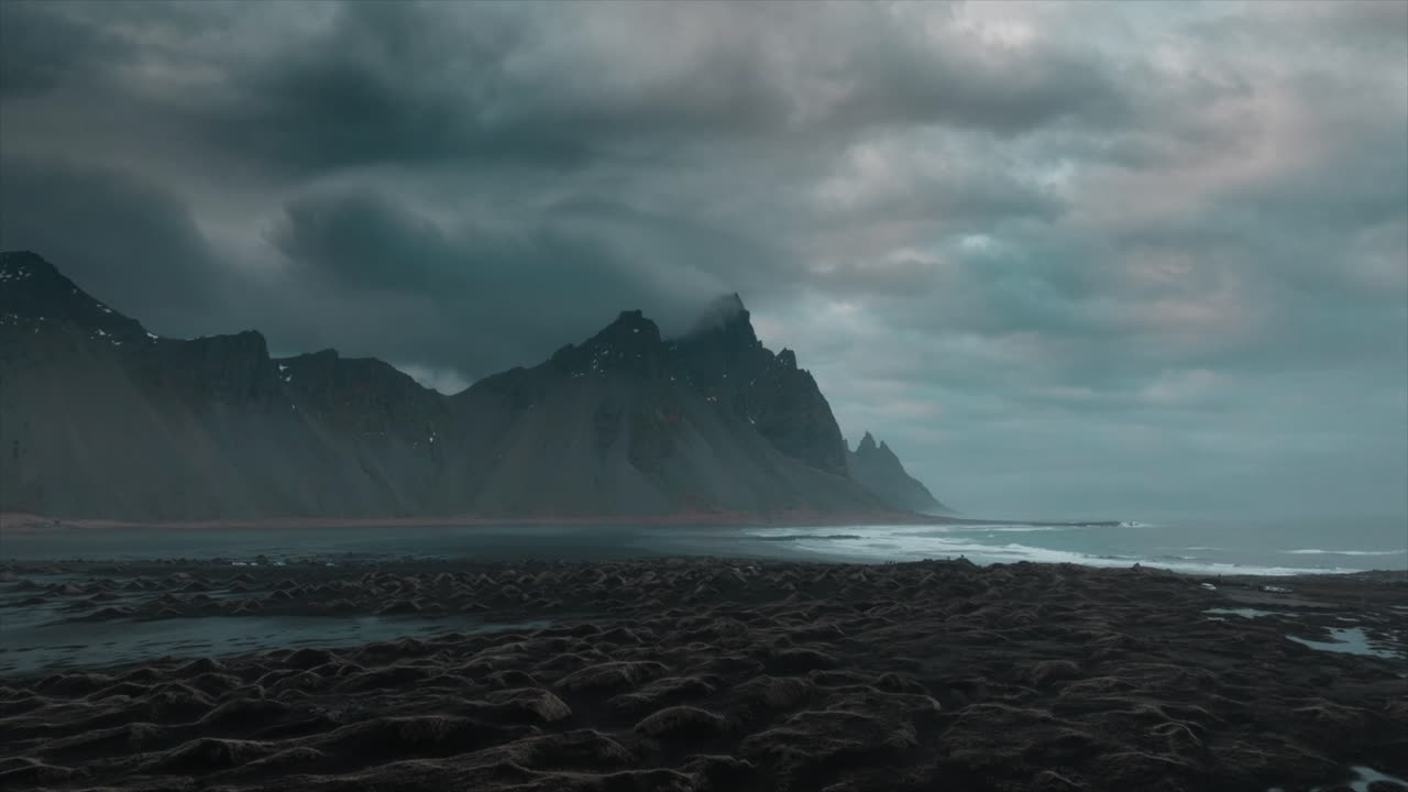 imágenes de drones sobre la playa de arena negra de stokksnes, mostrando nubes dramáticas y la majestuosa montaña vestrahorn, islandia