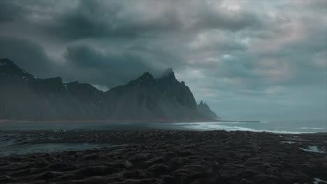 drone footage over stokksnes black sand beach, showcasing dramatic clouds and the majestic vestrahorn mountain, iceland