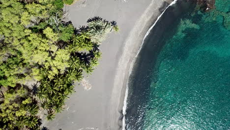 antena de agua azul cristalina de la playa de arena negra de roca de lava en la isla grande de hawaii