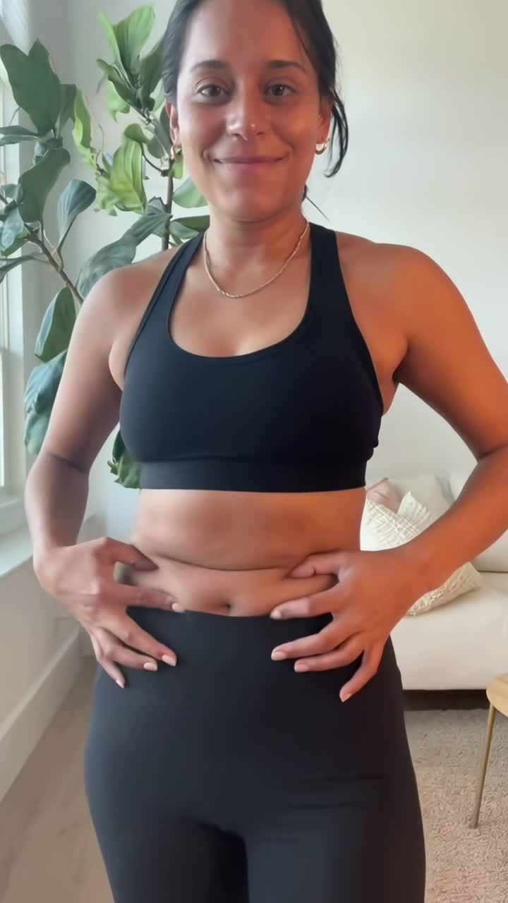 Donna che si pizzica la pancia e sorride, abbracciando la body positivity