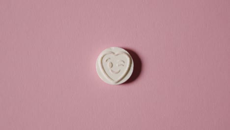 Hand,-Die-Herzbonbons-Mit-Zwinkerndem-Emoji-Auf-Rosa-Hintergrund-Aufhebt