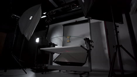 cámara automática en estudio tomando fotografías de un taladro en una mesa de vidrio