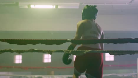 chica atlética en casco de boxeo subiendo al ring para entrenar con un compañero de entrenamiento