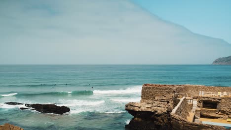 portugal guincho beach with waves crashing, cloudy day, near shore with surfers