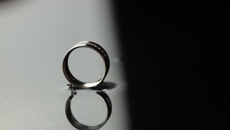 wedding rings on black, white water surface. groom ring rolling to bride's ring