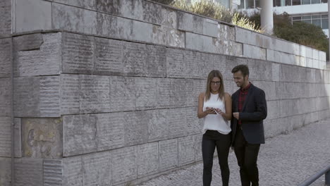 joven pareja feliz usando un teléfono inteligente en la calle