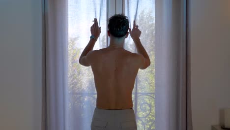 man opening balcony doors to bright morning light