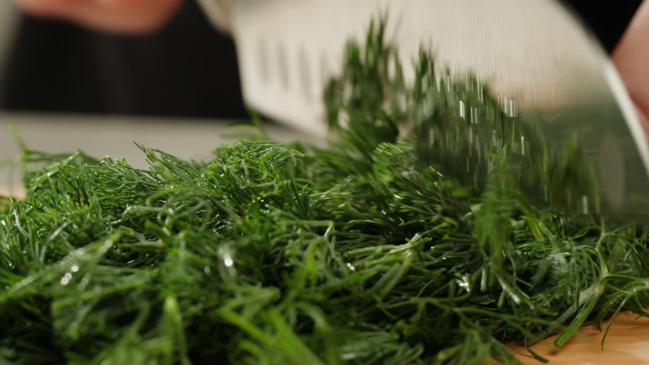 Cutting dill, chef cut dill with knife on a wooden board, close up at home, vitamin vegan greens.
