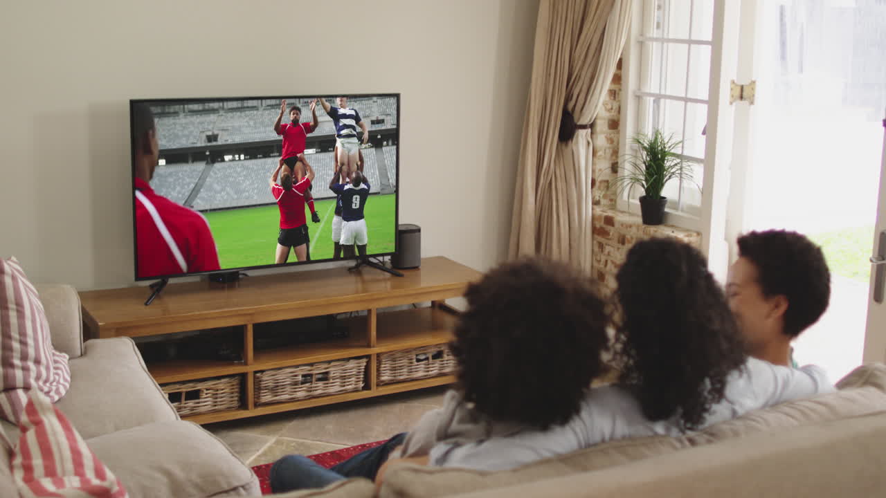 Famiglia felice seduta a casa insieme che guarda una partita di rugby in TV