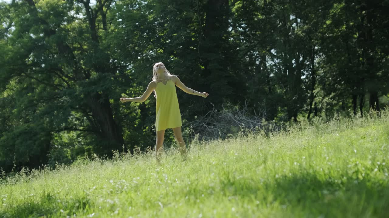 Kobieta w żółtej sukience tańcząca wdzięcznie w letnim parku