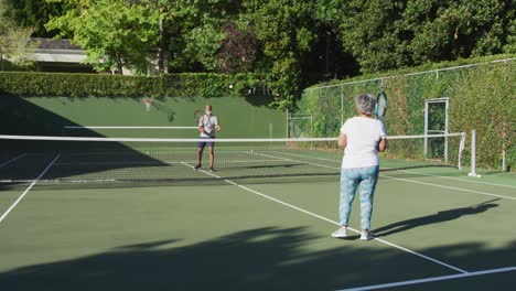 pareja de mayores afroamericanos jugando al tenis en la cancha de tenis en un brillante día soleado