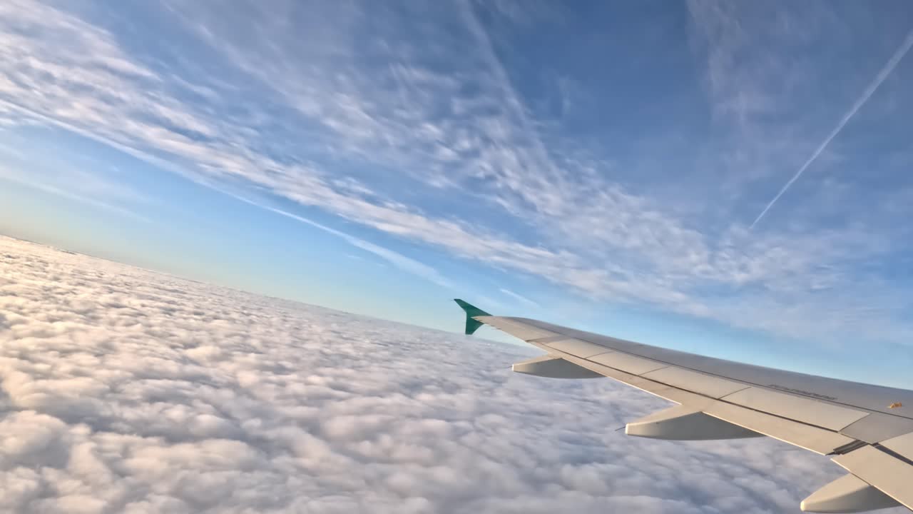 View of an airplane wing above the clouds during a flight, clear skies, peaceful journey