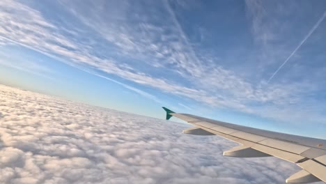 view of an airplane wing above the clouds during a flight, clear skies, peaceful journey