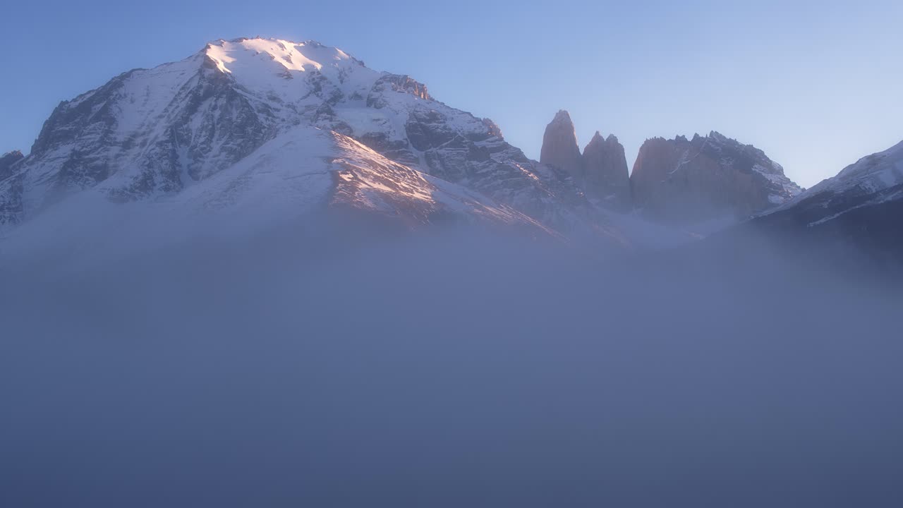 Ripresa aerea ascendente sopra le nuvole che rivela le montagne della Regione di Magellano durante l'ora d'oro