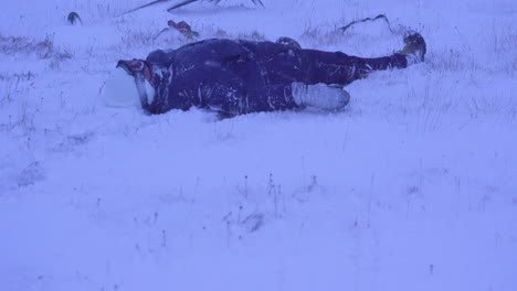 Tilt-up,-woman-lying-motionless-on-snowy-ground-near-anchor-while-snowstorm