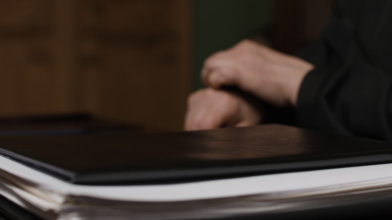 Person in a black robe handling documents in an office