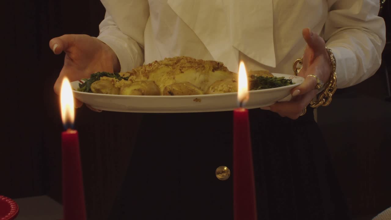woman gracefully serves golden bacalhau codfish in warm candlelit setting, Portugal