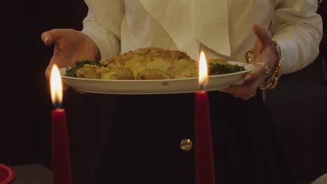 woman gracefully serves golden bacalhau codfish in warm candlelit setting, portugal