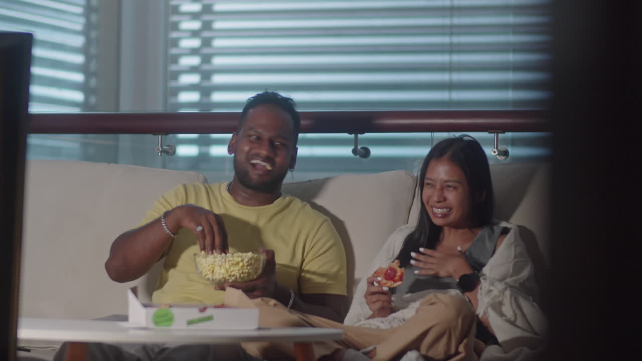 Couple Watching TV with Snacks in Evening at Home