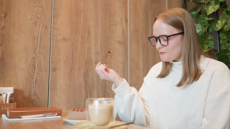 young girl sitting in cozy cafe eats chocolate dessert with joyful expression, savoring each bite with eyes closed and head tilted slightly, conveying satisfaction and enjoyment of sweet indulgence
