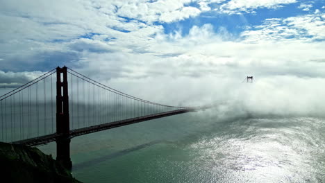 aerial drone shot above golden gate bridge in san francisco, usa with white clouds passing by at daytime