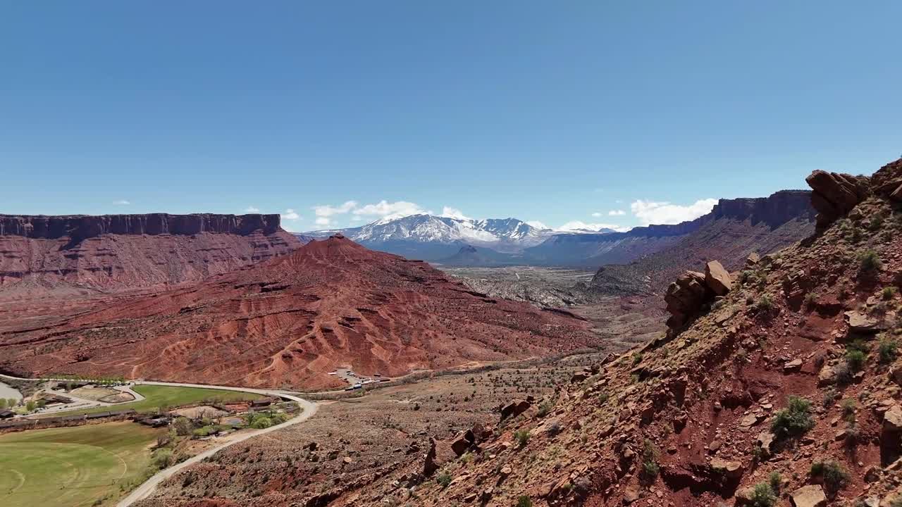 Drone Ascending over Hill Revealing Mountains in background with Patches of Snow, La Sal Mountains in Utah