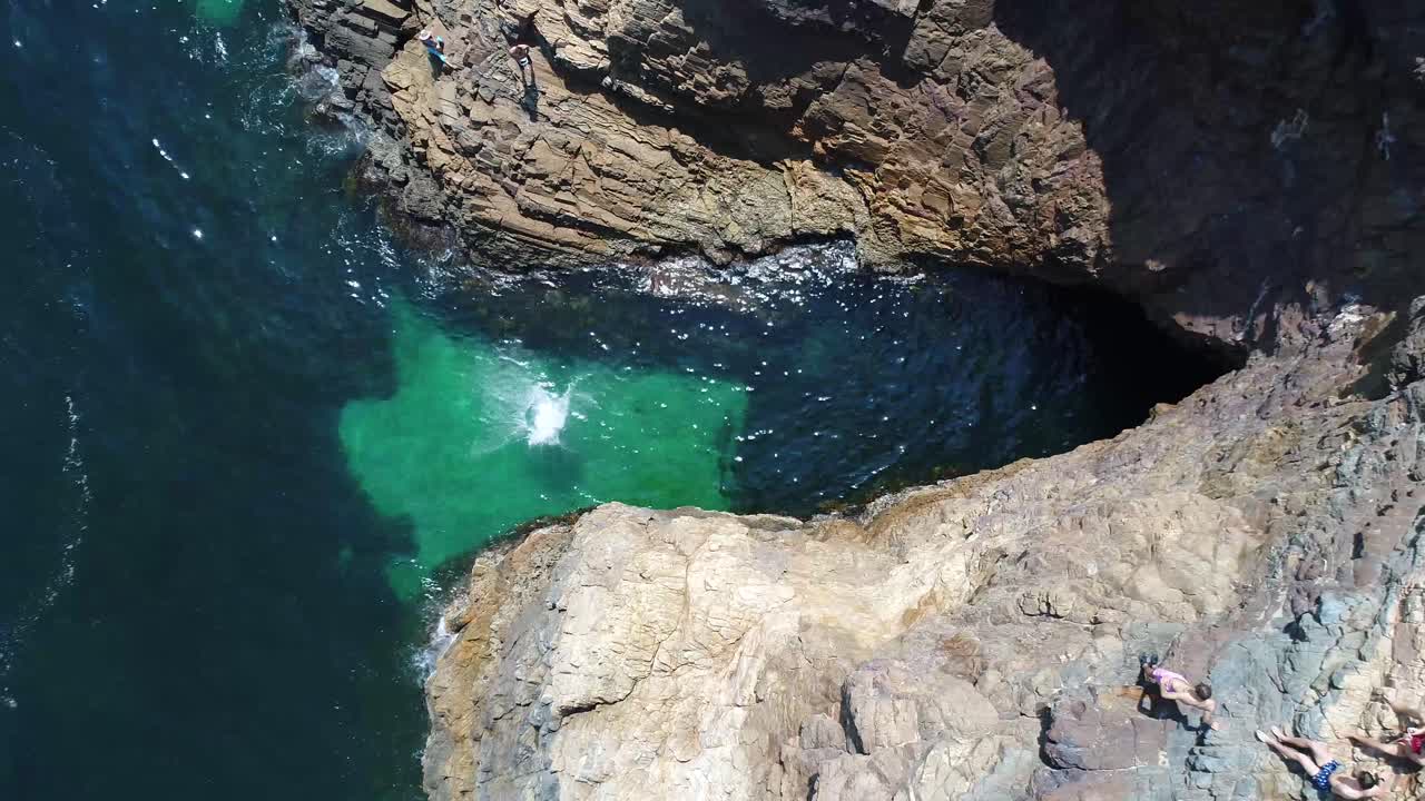 Top down shot of tourist jumping off cliff into pristine water at Second Valley, South Australia